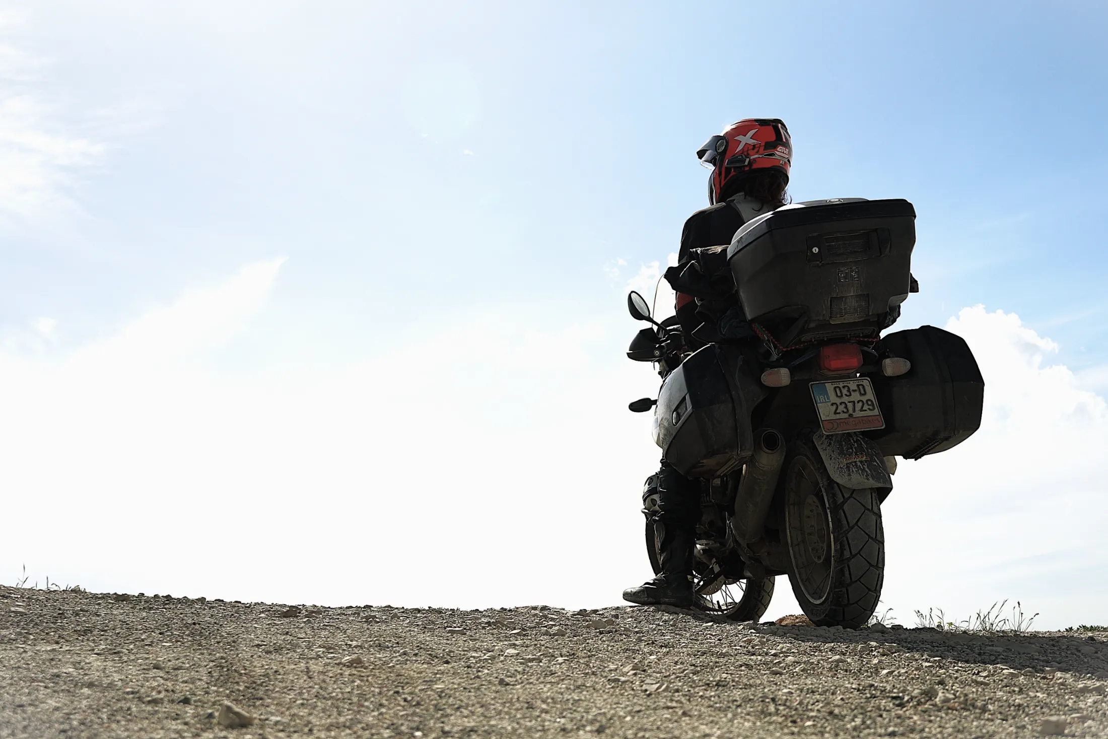 A loaded BMW R1150GS and its rider in silhouette against a wide sky